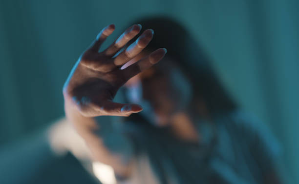 Mujer protegiéndose el rostro, representando el miedo y la violencia