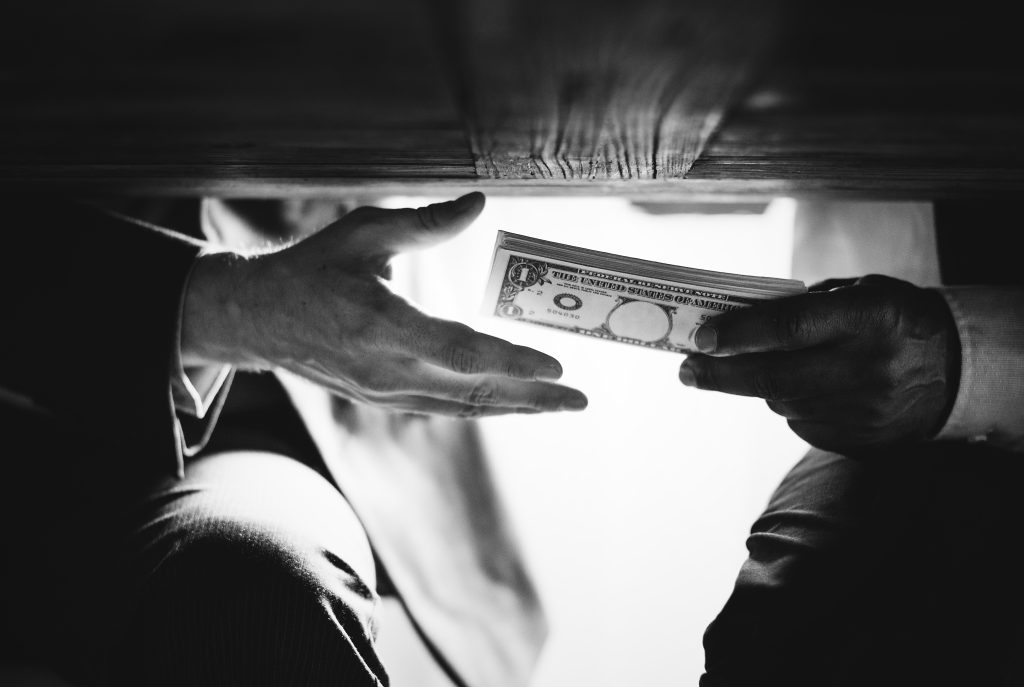 manos pasando dinero debajo de la mesa