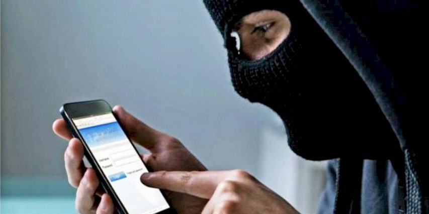 Persona con el rostro cubierto utilizando un teléfono celular, simbolizando amenazas digitales y presión económica ilegítima.