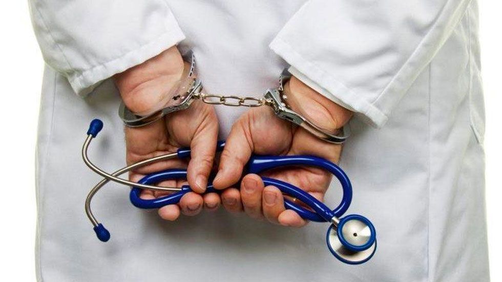Médico con esposas sosteniendo un estetoscopio, imagen representativa de la responsabilidad penal médica y la negligencia en la atención de la salud